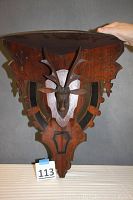 Front view of triangular shelf showing carved deer head and black accents