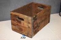 Full view of the rectangular wooden crate showing natural wood and painted lettering on side, with finger hole cutouts