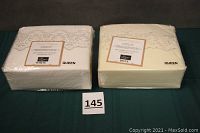 Two queen-sized sheet sets side-by-side in original packaging, one white and one bone colored, both showing bridal lace detail on top.