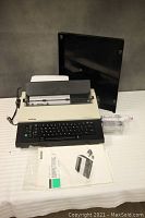 Brother Compactronic #1 electric typewriter with user manual, extra ribbon cartridges, and power cord laid out on a table.