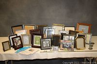 Lot of 31 assorted picture frames displayed on table, showing variety in size and frame materials such as wood and metal.