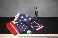 Photo showing three flags folded and standing folk art weather vane figure with 19th-century man in top hat holding paddles.