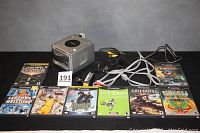 Image of Nintendo GameCube console with power and AV cables, 8 boxed games arranged in front, showing the console and games included in the lot.