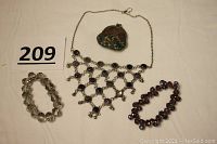 Photo shows entire lot with necklace, two bracelets, and coin purse laid out flat on a surface with lot number.