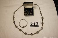 Photo showing full jewelry set including necklace laid flat, bracelet, and two pairs of earrings in a box.