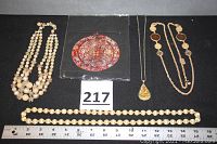 Group display of five items: three necklaces, one necklace with pendant, one beaded necklace, and one round embroidered purse.