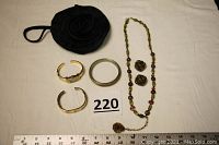 Full lot showing black wrist purse, two gold-tone bracelets, colorful glass bead necklace, gold-tone earrings and necklace set, and watch with matching bracelet.