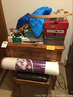 Full view of the walnut veneer sewing machine table, stool, and items on table including scissors, yarn, and boxes.