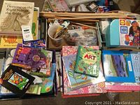 Overview of assortment of children's arts and crafts supplies including books, yarn kit, markers, stencils and wooden dowels