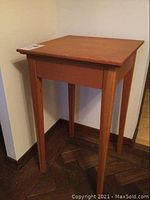 Angle view of wood side table showing legs and top surface.