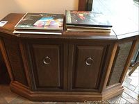 Front of the walnut stereo console showing central cabinet doors and LP records on top.