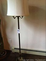 Full view of the vintage floor lamp showing the lamp shade and overall height against a wall.