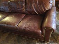 Right side front view showing seat cushions, rolled arm with brass nailhead trim and patina