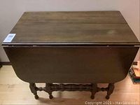 Top view of the table folded down with leaf sides closed showing rectangular wooden surface and some surface wear.