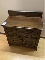 Front view of vintage wood side board showing three drawers and one cupboard with glass insert.
