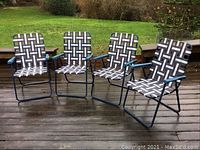 Set of four vintage style folding lawn chairs arranged on a wooden deck outdoors, showing full chairs and pattern detail.