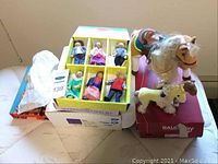 View of all items including boxed Melissa & Doug wooden family dolls, loose family dolls, and 2 toy horses on mattress surface.