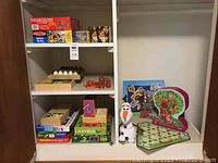 Overview of toys and puzzles in shelf including boxed puzzles, Olaf plush, floor puzzles, and wooden toys.