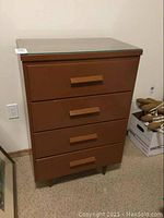 Front view of brown solid wood four drawer dresser with glass top and large rectangular wooden handles.