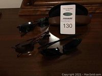 Three pairs of sunglasses arranged in front of a brown leather case