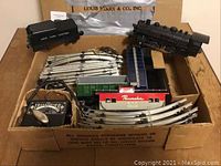 Full set view inside original box showing steam engine, grain car, caboose, tracks and transformer controller