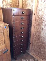 Front view of tall chest showing eleven drawers and brass-tone knobs
