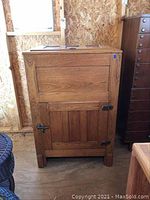 Front view of vintage wooden ice box showing panel door and metal latch hardware