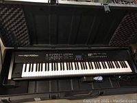 Full view of Roland RD-700SX stage piano seated in foam-padded hard case with lid open