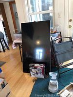 TV panel leaning upright against a table, mount box and other household items visible