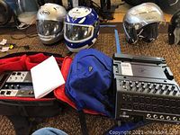 Wide overview showing two mixers side by side in soft case, helmets and bag in background