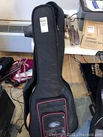 Closed soft-sided gig bag standing upright with front zippered pockets