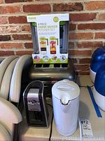 The lot with all appliances including Takeya drink maker set in box on top of a stainless steel KitchenAid toaster, white kettle, and Hamilton Beach can opener visible in front.