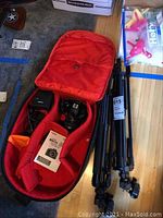 Red camera bag open showing camera body with lens, manual, charger and bag interior