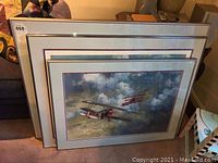 Three silver-tone framed aviation prints stacked upright