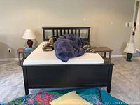 Front view of queen bed frame with mattress and comforters visible