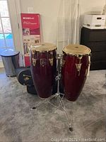 Pair of LP Aspire congas mounted on double stand with carrying cases in background