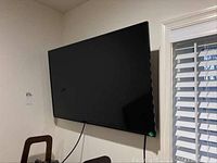 Front view of the Vizio TV mounted on the wall with visible power cord hanging.