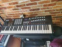 Full view of keyboard and stool against brick wall
