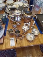 Full view of all silverplate and pewter serving items arranged on wooden table