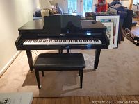 Front view of black digital piano with matching bench in room