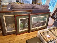 Three framed prints leaning against couch