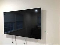 Front view of wall-mounted Panasonic flat-screen TV with cables hanging below