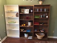 Full overview of three shelves containing assorted pottery, tins, platters, candle, basket, and other items.