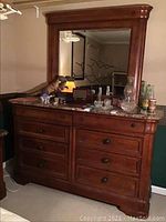 Front view of the dresser with marble top and attached mirror showing drawers and knobs. Items on top not included.