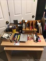 Wooden desk organizers filled with various office supplies on a desk showing condition and contents.