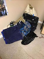 Blue and black inflatable air mattress and assorted tote bags and suitcase placed on beige carpet.