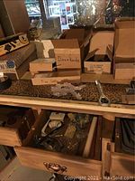 Boxes and drawers containing various door knobs and hardware pieces on a leopard print surface.
