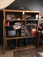 Wooden shelving unit containing stereo and audio equipment, CD cases, records and small CRT television.