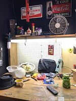 Overview of workbench with assorted workshop items including containers, tools, and a small decorative frog figurine.
