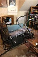 Full view of treadmill with exercise table and golf carry bag; shows treadmill frame and padded areas, stored indoors, visible wear and dirt.